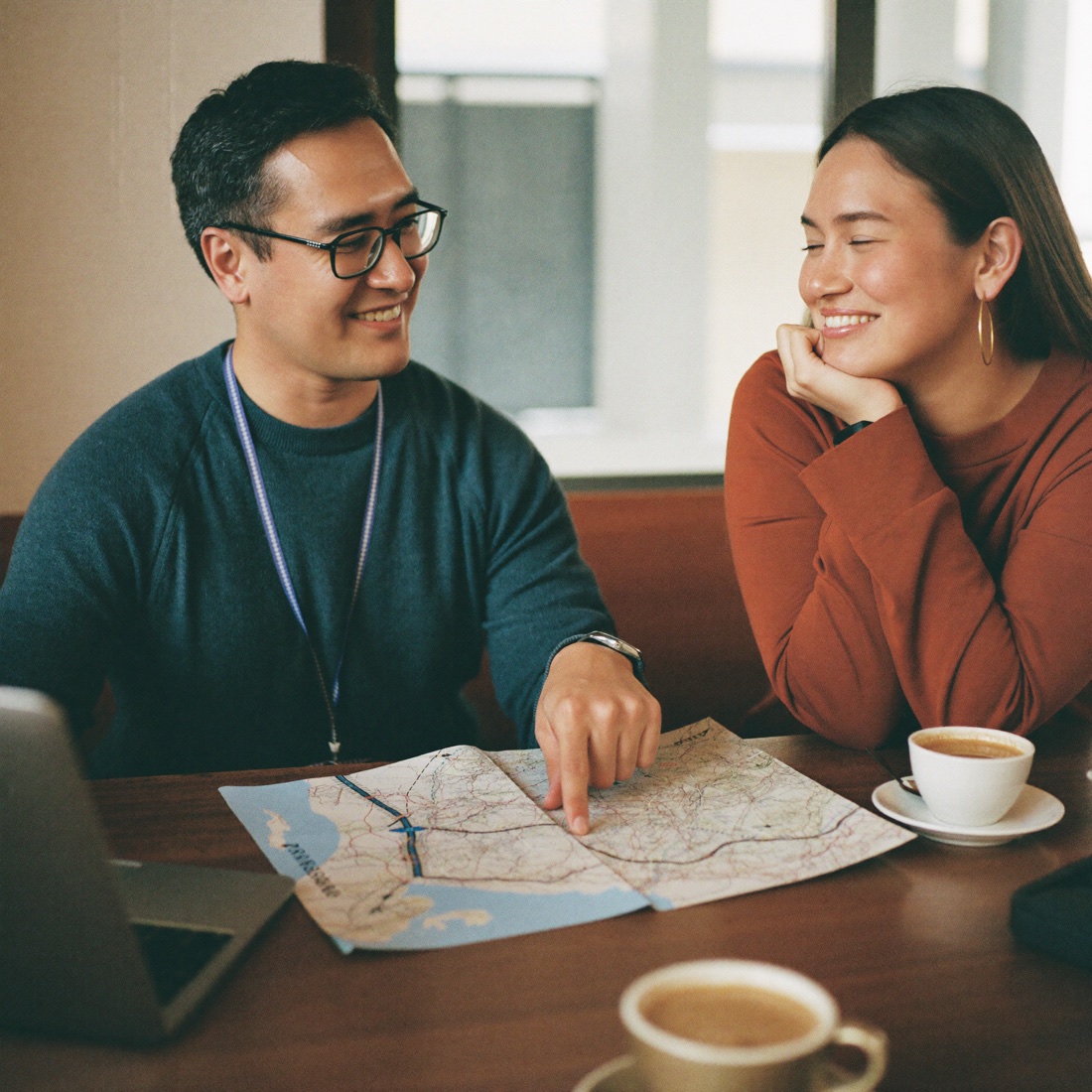 Un asesor y una viajera planifican una ruta sobre un mapa en un café