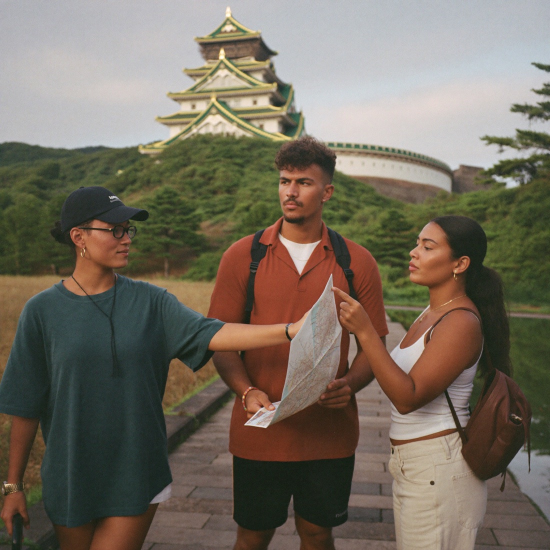 Tres viajeros latinos consultan un mapa cerca de un castillo japonés