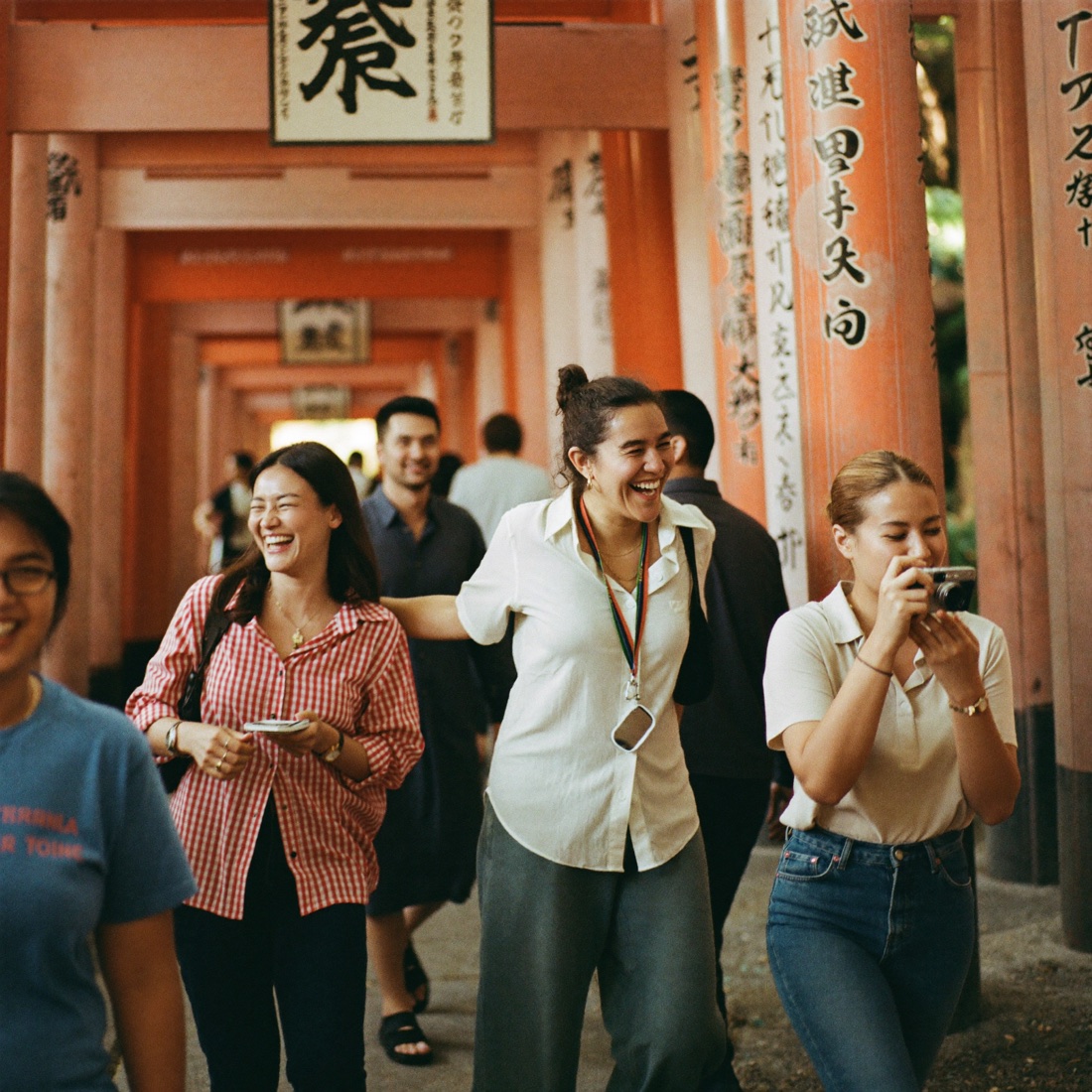 Grupo de viajeros ríe con su guía entre los torii de Fushimi Inari
